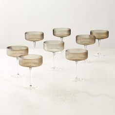 six wine goblets sitting on top of a white table next to each other