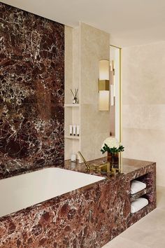 a bathroom with marble walls and flooring next to a bathtub in the corner