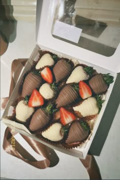 a box filled with chocolate covered strawberries on top of a table