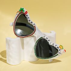 two white sunglasses with the words merry christmas written on them and decorated with red flowers