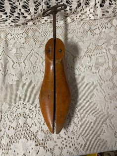 an old wooden object is hanging on a lace tablecloth with a hook in the middle