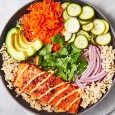 a bowl filled with rice, cucumbers, carrots and other veggies