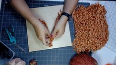 someone is making something out of yarn on a cutting board with scissors and other crafting supplies