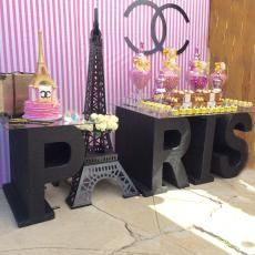 there are two tables that have candy in front of the eiffel tower on them