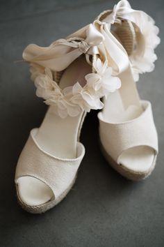 a pair of white high heeled shoes with ruffles and bows on them