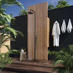 an outdoor shower with two white towels hanging on the wall next to trees and bushes