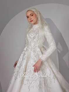 a woman in a white wedding gown with a veil on her head and hands on her hips