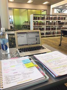 an open laptop computer sitting on top of a desk next to a book shelf filled with books