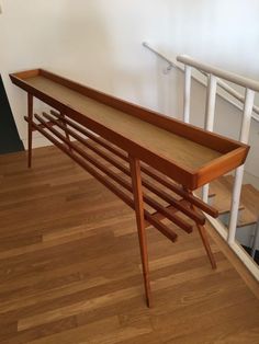 a wooden table sitting on top of a hard wood floor next to a stair case