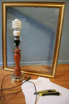 a light bulb sitting on top of a wooden table next to a framed photo and paper