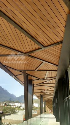 an outdoor covered walkway with glass railings and wood slats on the side of it