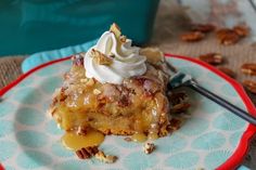 a piece of cake sitting on top of a plate with whipped cream and pecans