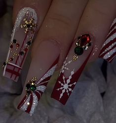 a woman's hand with red and white nail polish on it, decorated with christmas decorations