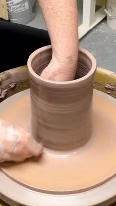 a person is making a vase out of clay on a potter's wheel,