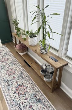 a wooden bench sitting next to a window with potted plants on top of it