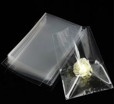 two clear plastic bags with a white rose in the middle one has a black background