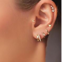 a close up of a person wearing gold ear rings with diamond hearts on the side