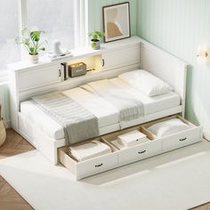 a white bed with drawers underneath it in a room