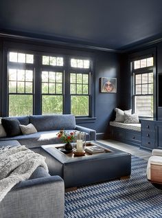 a living room with blue walls and furniture in the corner, along with large windows