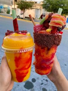 two people holding up drinks with fruit on the top and one has strawberries in it