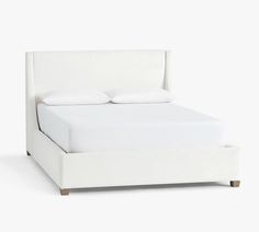 a bed with white linens and pillows on it's headboard is shown