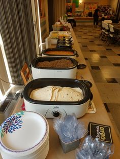 several different types of food are lined up on a table in a restaurant, including tortillas and burritos