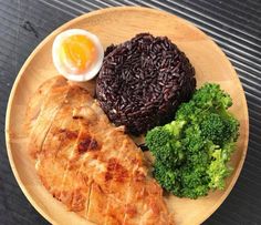 a plate with rice, broccoli and an egg on it next to some kind of meat