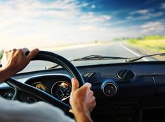 a man driving a car down a road with his hands on the steering wheel,