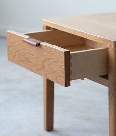 a wooden table with two drawers on one side and an open drawer on the other