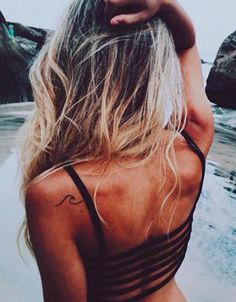 the back of a woman's head with her hair blowing in the wind at the beach