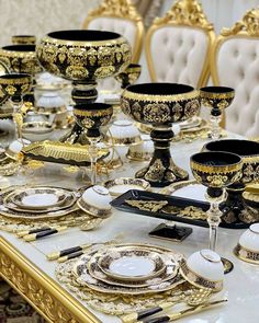 the table is set with black and gold dishes