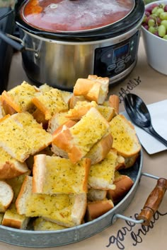 a bowl full of bread sitting on top of a table next to a crock pot