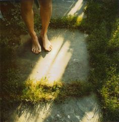 a person standing in the grass with their bare feet