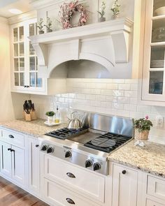 a kitchen with white cabinets and marble counter tops, along with a stainless steel stove top oven