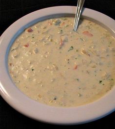 a white bowl filled with soup sitting on top of a black table next to a silver spoon