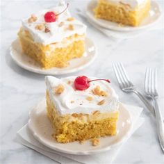 three pieces of cake with white frosting and cherries on plates next to forks