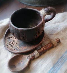 two wooden spoons sitting on top of a table next to a cup and saucer