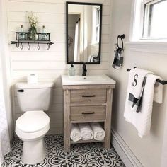 a white toilet sitting next to a sink in a bathroom under a mirror and towel rack