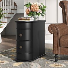 a brown chair sitting next to a black table with flowers on it and a book shelf