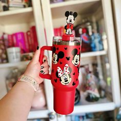 a person holding a red cup with mickey mouses on it