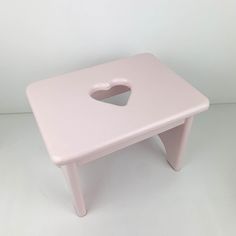 a small pink table with a heart shaped hole in the center on it's legs