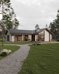 a modern house in the middle of a grassy area with a gravel path leading to it