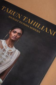 a woman in a white dress is standing next to a black book cover with the title tarun tahliani journey to india modern