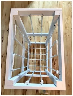 the inside of an unfinished window frame with ropes and screws in it on a wooden floor