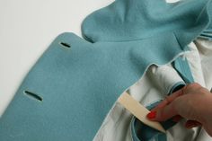 a person holding a toothbrush in front of a piece of fabric with holes on it