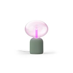 a pink light sitting on top of a green table next to a white wall and floor