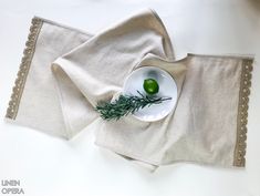 a white plate topped with an apple on top of a table next to napkins