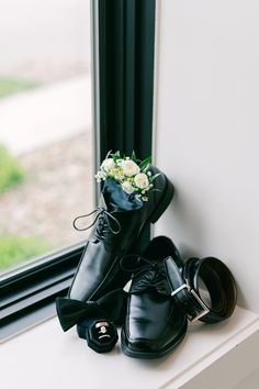 a pair of black shoes sitting on top of a window sill next to a bouquet of flowers