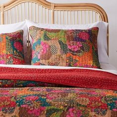 a bed with colorful pillows on top of it and a wooden headboard in the background