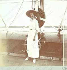 an old black and white photo of a woman wearing a hat standing in front of a plane